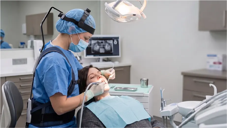Dental professional wearing a neck support exoskeleton during patient treatment